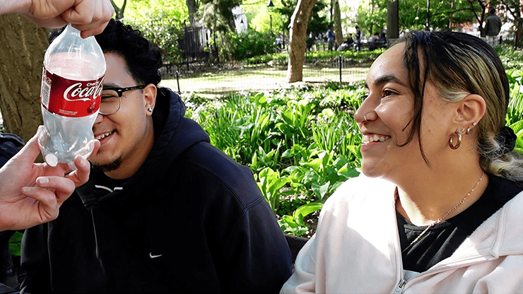 Coin Shot by Alex Latorre 5 Magie de rue en plein air avec deux jeunes adultes souriants, un d'eux tenant une bouteille de Coca-.