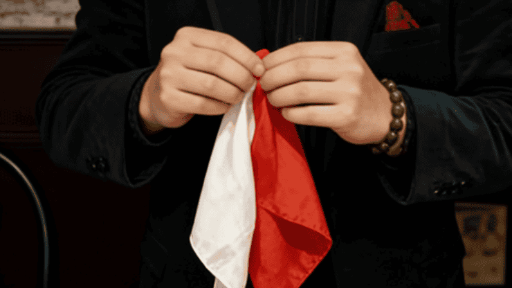 Personne tenant un tissu rouge et blanc pour un tour de magie.
