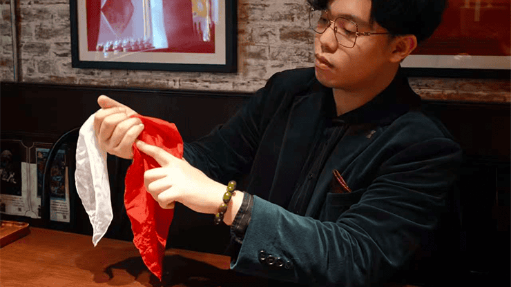 Jeune magicien manipulant un foulard rouge et blanc en magie.